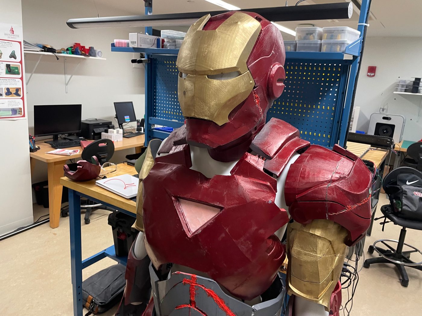 Front left view of the finished suit in the makerspace, showing the helmet, chest piece, and shoulder armor